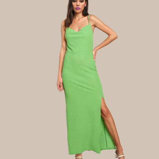 Woman wearing a sleeveless lime green maxi dress with a side slit, styled with strappy heels, standing against a neutral beige background.