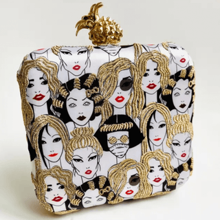 Square clutch bag featuring embroidered illustrations of diverse glamorous women with gold thread detailing and a gold pineapple clasp on top, styled against a neutral background.