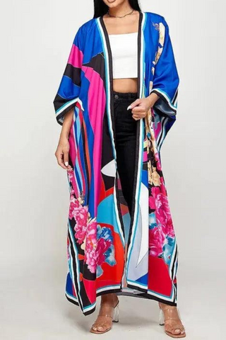 Embrace vibrant island flair with The Santo Domingo Kimono, a stunning statement piece featuring a mesmerizing mix of bold geometric patterns and vibrant florals. Designed in a rich palette of blues, pinks, and warm tones, this flowing kimono wraps you in soft, lightweight fabric that drapes elegantly over any outfit. Perfect for layering, this one-size kimono adds a touch of artistic sophistication to your look, whether you’re strolling along the beach or turning heads at a city rooftop party. 